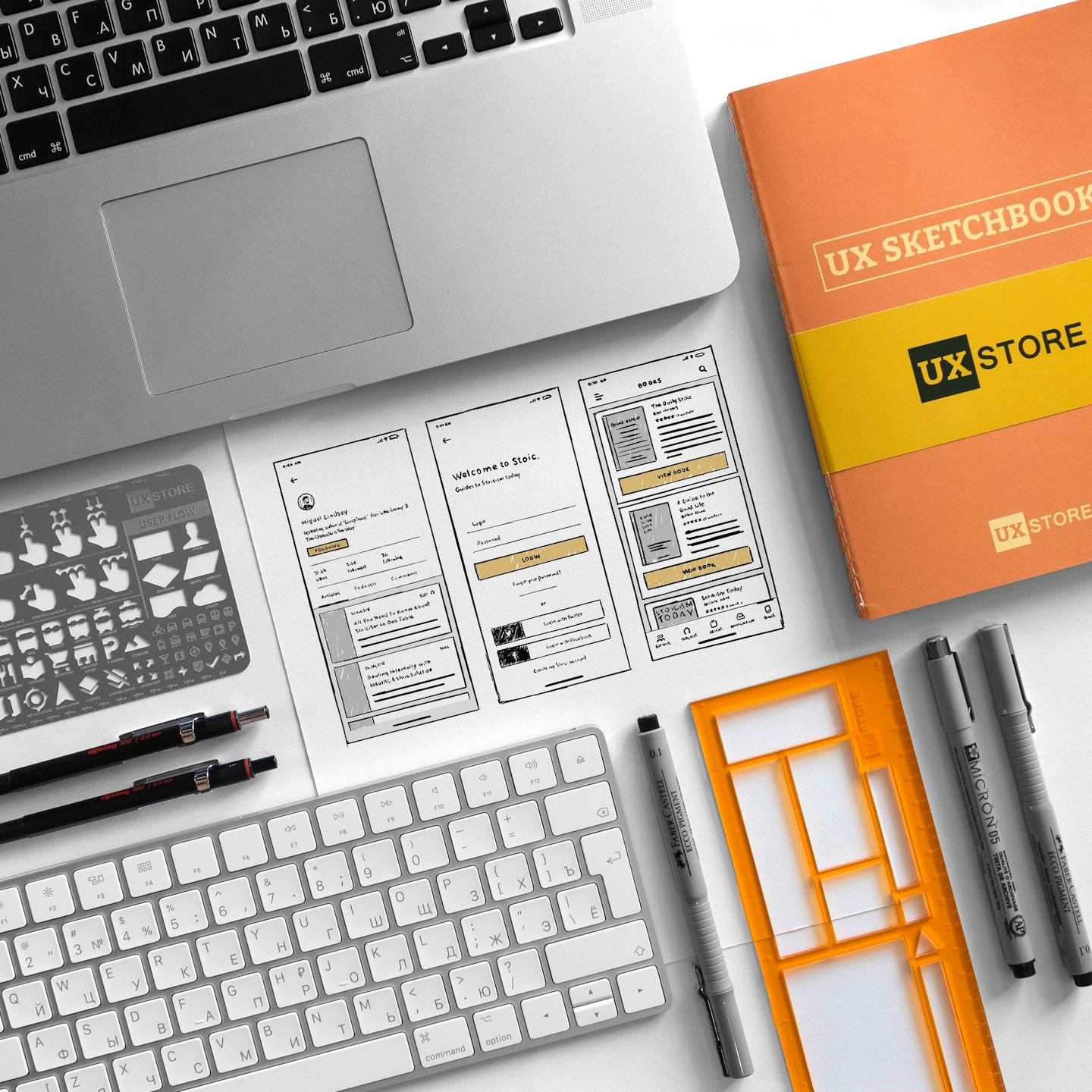Laptop, Drahtgitter-Mockups und UX-Design-Tools auf einem weißen Schreibtisch.