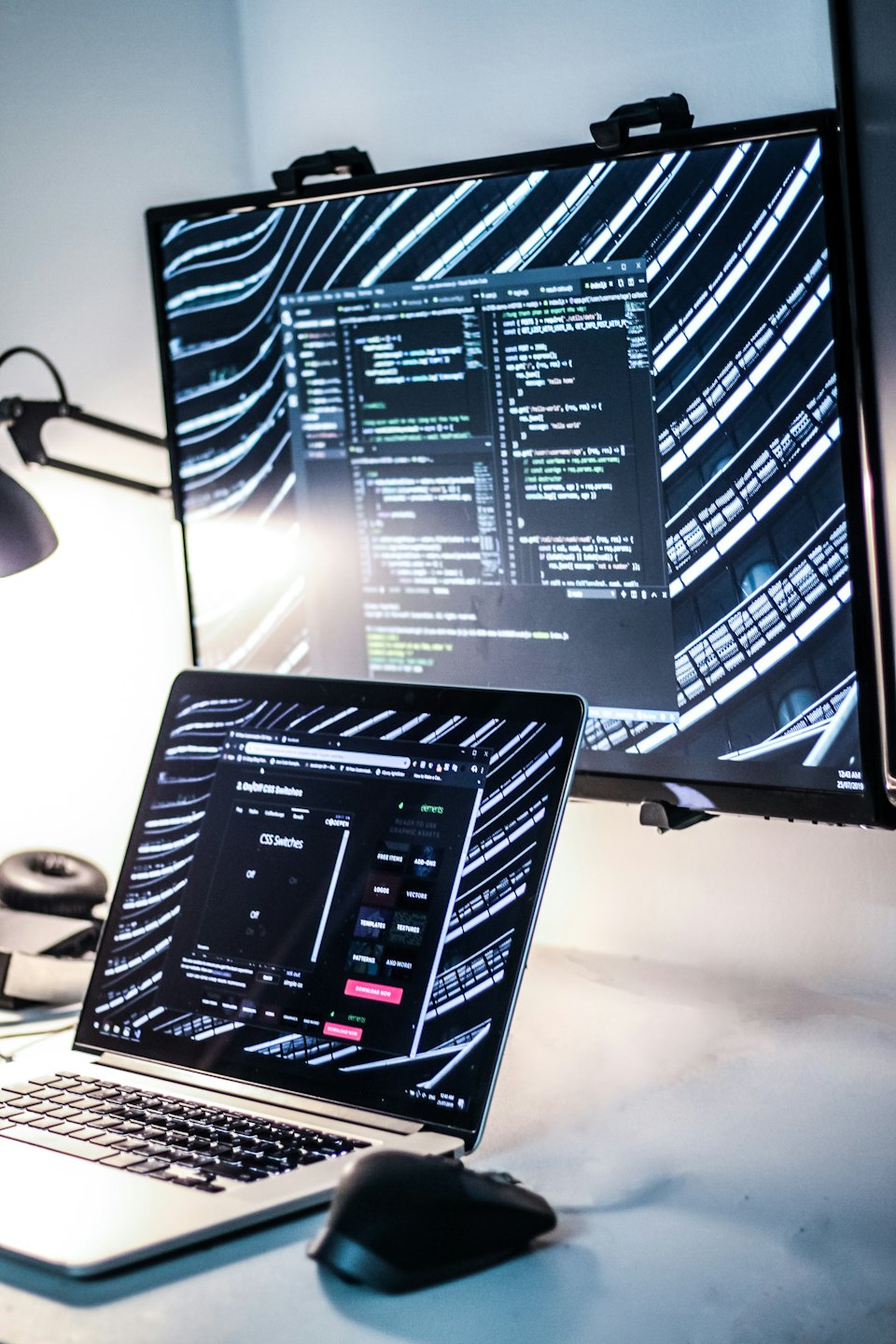 Laptop und Monitor mit Code in einem modernen Büro.