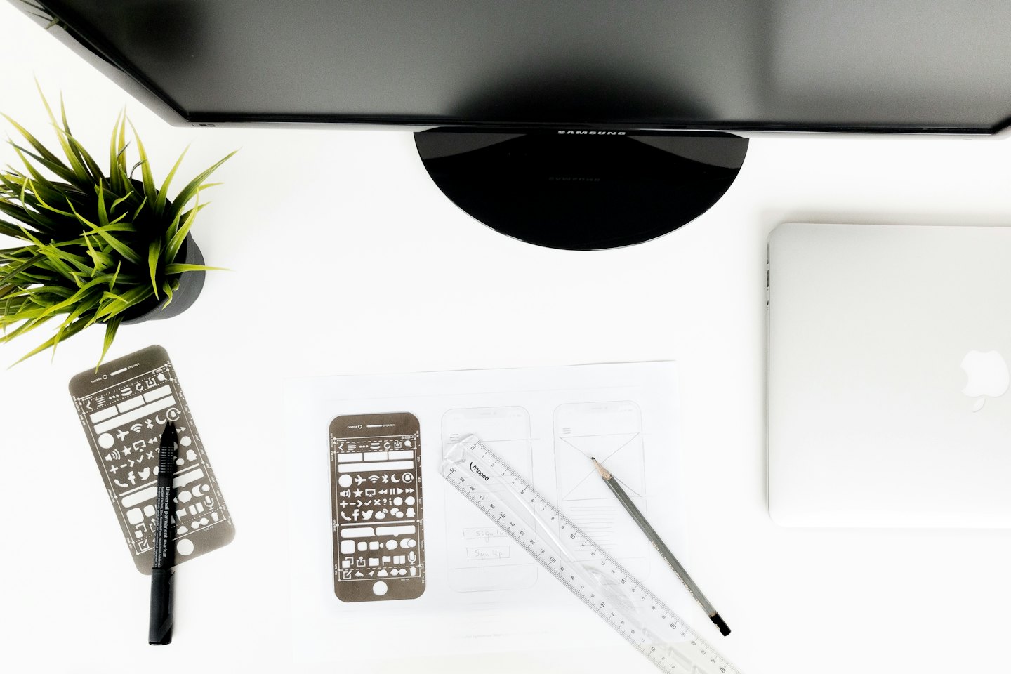 Schreibtisch eines Designers mit Laptop, Monitor und Zeichenutensilien.